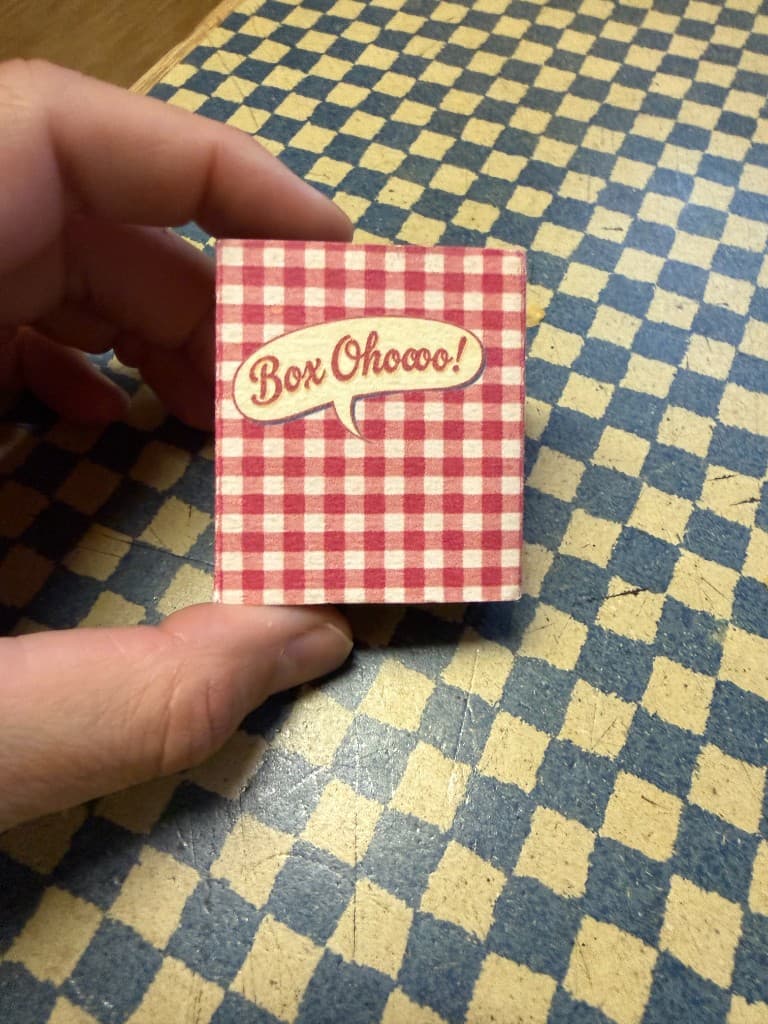 Closed Boxoho matchbox-sized Tiny Art Surprise held between two fingers