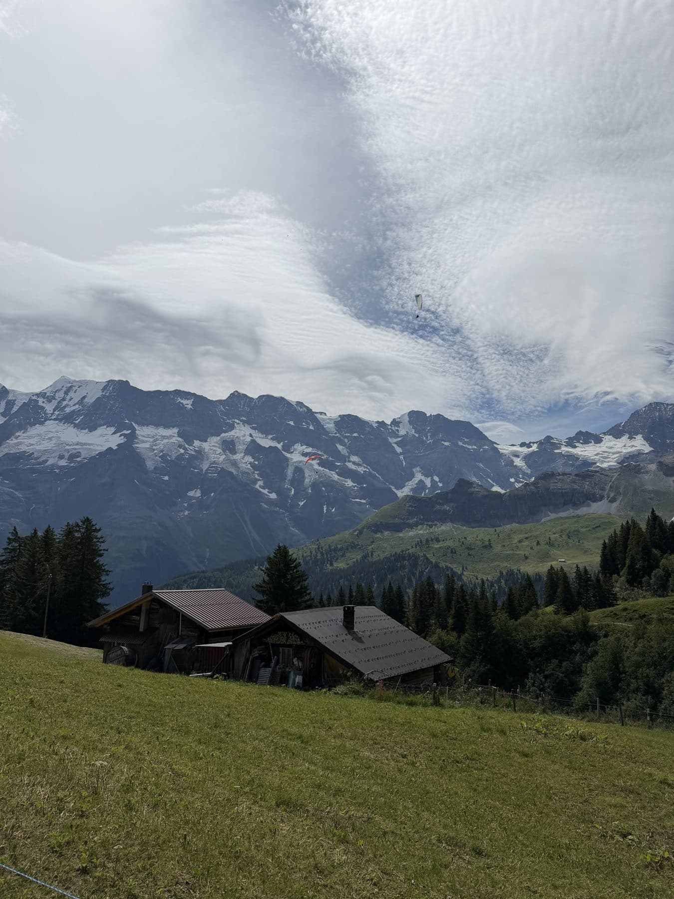 Alpine huts and mountains with paragliders in the sky